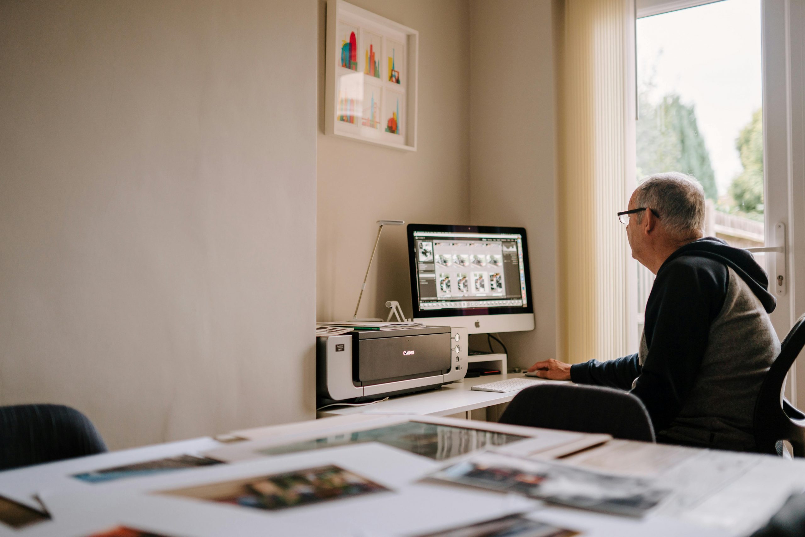 Elderly man engaged in photo editing at home office, showcasing a cozy and focused workspace.