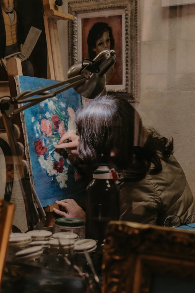 A focused artist paints a vibrant flower canvas in a Paris art studio.