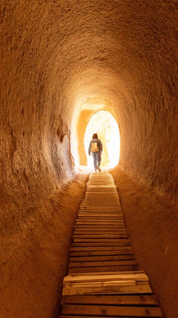 A lone traveler walks through a tunnel in the sandy rock formations of Cappadocia, Türkiye.