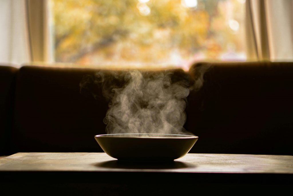 pexels-photo-5820105-5820105 A steaming bowl of soup on a wooden table indoors with soft autumn light through a window.